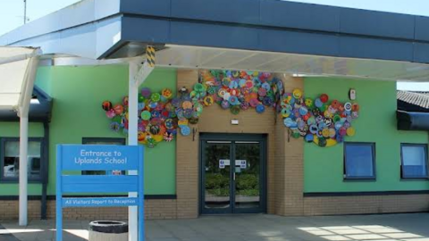 The front entrance of Uplands School in Swindon with bright green-painted walls and a colourful display of artistic decorations above the double doors.