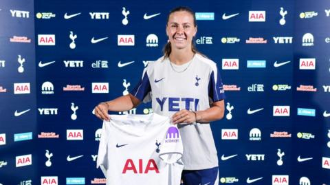 Victoria Pelova faces the camera while holding a Tottenham shirt