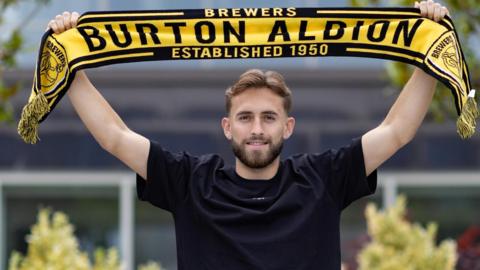 Jack Cooper-Love holds up a Burton Albion scarf