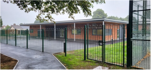 A wide shot of the school and the green fence around it