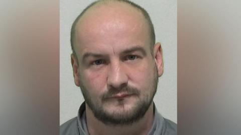 Mugshot of Paul Stoddart. He has a very short, dark beard and a shaved head.