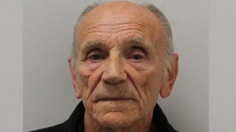 Mugshot of Ronald Evans. He has short light grey hair which is receding. He is looking directly at the camera with a blank expression. 