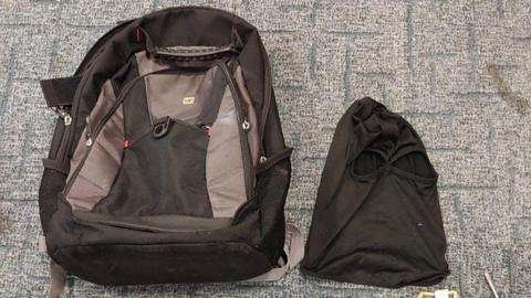 A black and grey backpack on the floor next to a black balaclava