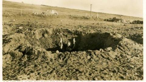 Man holding rabbit in bomb crater