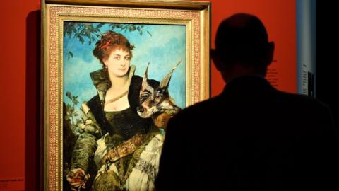 A visitor looks at a painting entitled The Falconer by Austrian artist Hans Makart