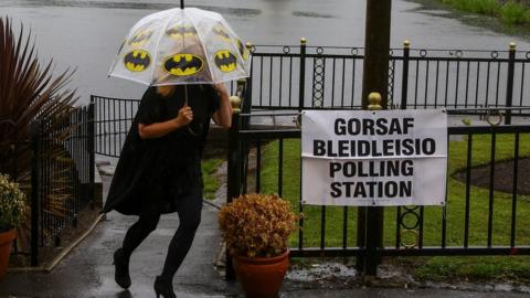 woman with umbrella leaving polling station