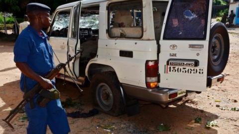 A Burundian policeman stands next to the shrapnel-riddled vehicle in which Tutsi General and security advisor to Burundi"s vice president Athanase Kararuza was killed on April 25, 2016 in Bujumbura