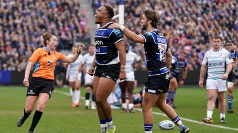 Max Ojomoh (centre) jumps in celebration after scoring as Tom de Glanville behind pats his shoulder 