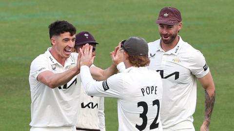 Surrey players congratulate Matt Fisher on taking a wicket
