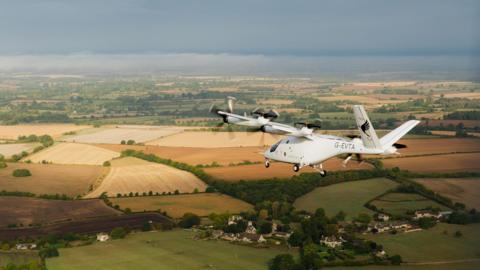 A Vertical VX4 flying above the Oxfordshire countryside on a cloudy day.