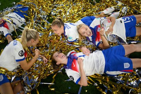 England's Leah Williamson, Georgia Stanway, Esme Morgan and Keira Walsh celebrate alongside the Euro 2025 trophy as they lay in ticker tape following the teams victory over Spain. Photo by Harriet Lander