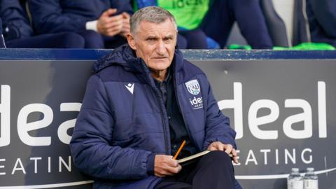 Tony Mowbray sat in the dugout with a notebook 