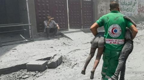 Emergency worker carry children rescued following an Israeli strike in Gaza City, 22 June