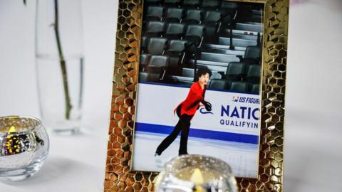 Gold framed photo of Spencer Lane skating with red shirt and black pants next to candles