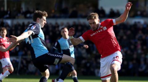 Adam Reach of Wycombe Wanderers (L) is challenges by Wrexham's Sam Smith 