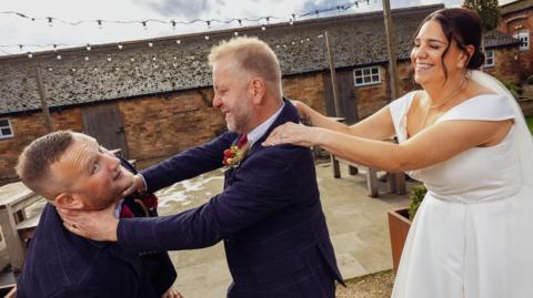 From left: Sam Myring, Martyn Disney and Michelle Disney dressed in wedding attire staging a mock fight