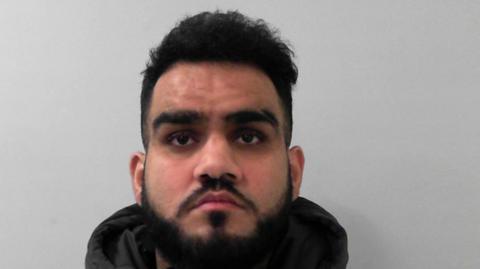 Mugshot of Mohammed Numaan, who has dark hair and a beard, looking straight at the camera.