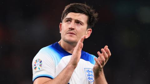 Harry Maguire clapping in an England shirt on the football pitch