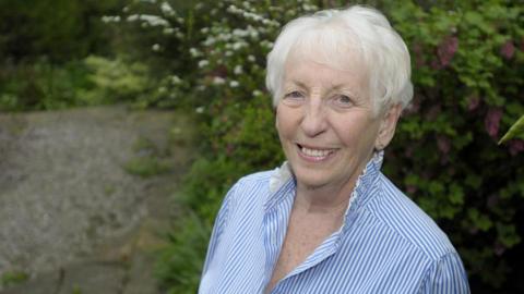 Celia Jordan smiling at the camera in a blue striped shirt 