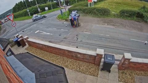 An overturned blue car with a grey car damaged too at the junction after a crash