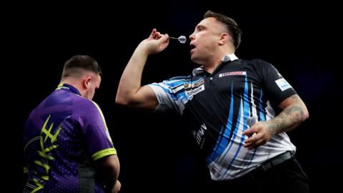 Gerwyn Price throws with Luke Littler in the background