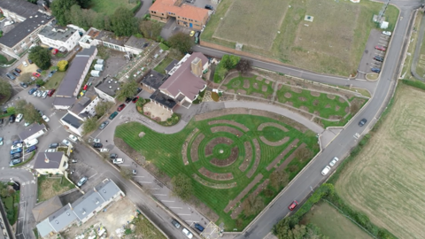 An aerial view above of fields surrounding buildings, central one of a crematorium in Jersey.