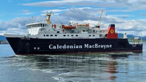 A black and white ship with red funnels. Caledonian MacBrayne is written on the side. There are blue skies and clouds in the background