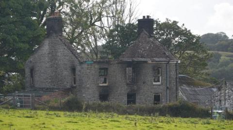 The burnt out remains of a cottage- style building in the countryside