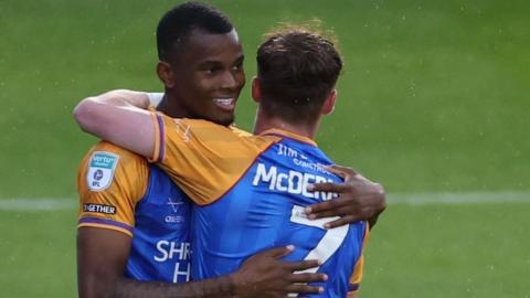 Bradley Ihionvien embraces a team-mate in celebration during a game for Shrewsbury Town