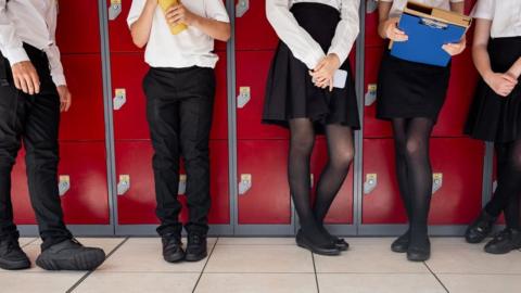Anonymous children standing in front of lockers in uniform