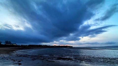 Dark clouds looming over a beach in Highland, Scotland.