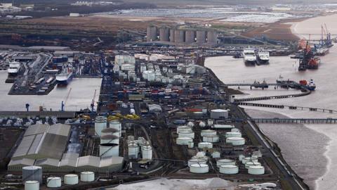 Aerial view of the port of Immingham there are a number of ships moored and many white gas storage tanks and shipping containers