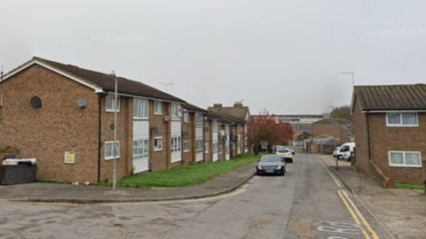 A street view image of a a residential street with brick properties either side of the road