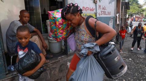 People carry belongings as they flee Port-au-Prince's neighbourhood of Nazon due to gang violence. Photo: 14 November 2024