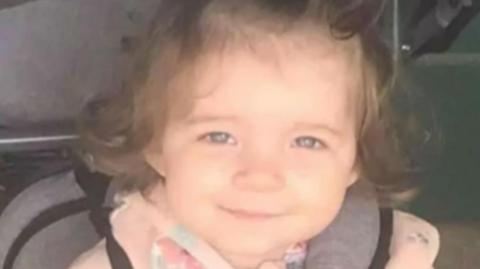 Head-and-shoulders image of Isabelle Rose Welsh. She is smiling directly into the camera and has dark hair. She is wearing a pink top.