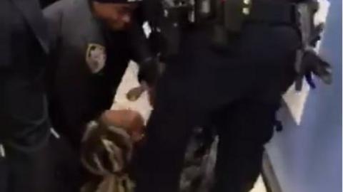 The video shows the mother on the floor as officers try to take her child