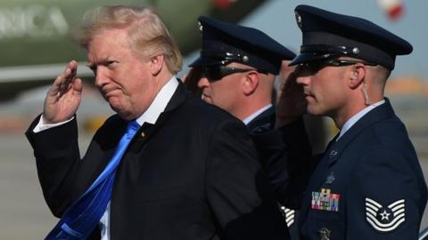 US President Donald Trump salutes a military aide at Newark Liberty Airport in New Jersey.