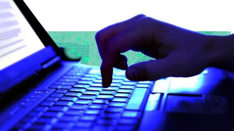 A hand hovers over a laptop keyboard