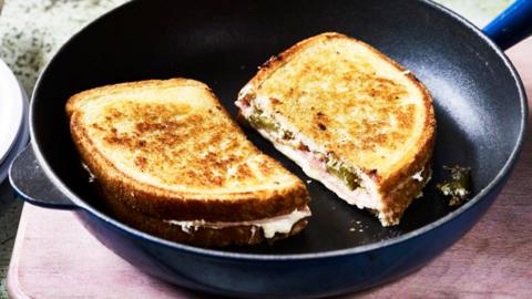 A toasted cheese sandwich on a black frying pan.