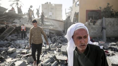 Palestinians are gathering around the destroyed home of the Hajj family following an Israeli bombardment at Nuseirat camp