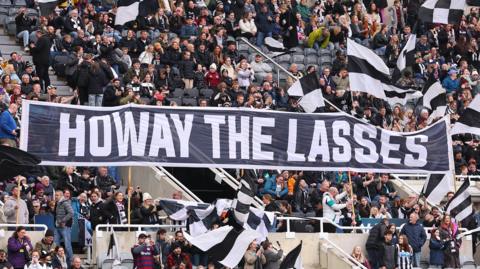 Newcastle fans hold up a banner saying Howay the Lasses at St James' Park