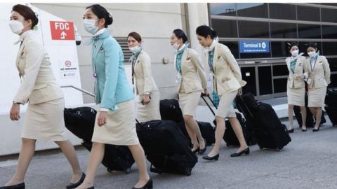 A flight crew from Korean Air, many wearing protective masks, depart the international terminal after arriving at Los Angeles International Airport (LAX) .