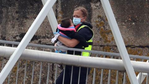 A Border Force officer carries a young child ashore in Dover