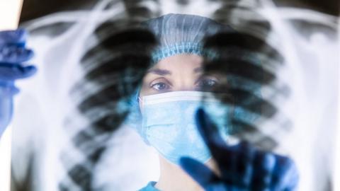 A radiologist inspects an x-ray of a person's lungs