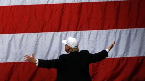 Donald Trump looks to the flag after he addressed supporters