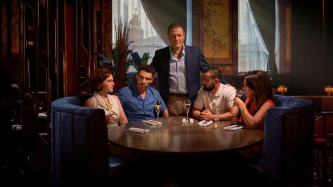 A group of people sat in a booth at a restraunt 