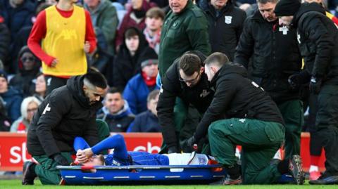 Wes Burns on a stretcher getting treatment