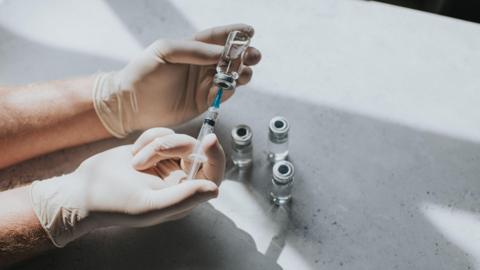 A medical professional holds a vaccine in hand