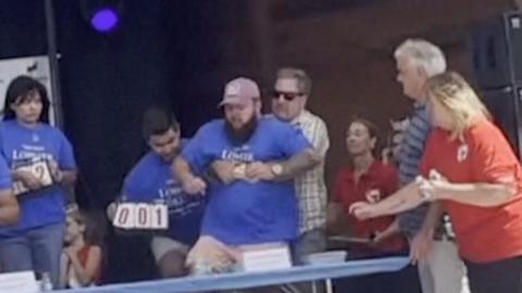 The man in blue is choking while the man hugging him from behind is helping him.