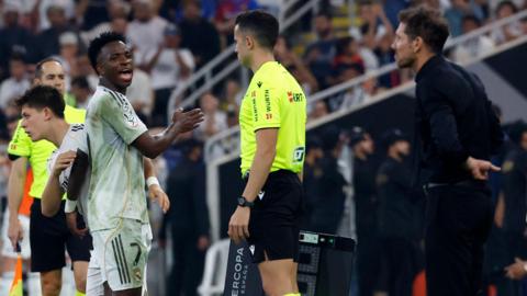 Real Madrid winger Vinicius Jr is substituted against Atletico Madrid, whose manager Diego Simeone watches from the touchline 